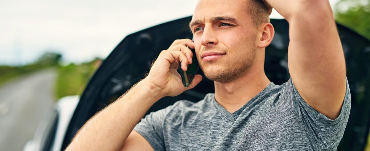Ilustrační stock: rozsvícená žlutá kontrolka motoru na palubní desce osobního automobilu, řidič sedí za volantem, civilně, bez loga