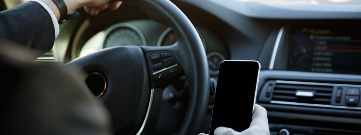 Ilustrační stock: řidič drží mobilní telefon v ruce u dálnice, na displeji formulář elektronické dálniční známky se státní poznávací značkou vozidla, civilně, bez loga