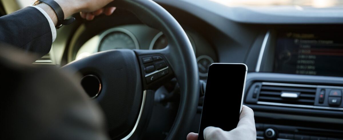 Ilustrační stock: řidič drží mobilní telefon v ruce u dálnice, na displeji formulář elektronické dálniční známky se státní poznávací značkou vozidla, civilně, bez loga