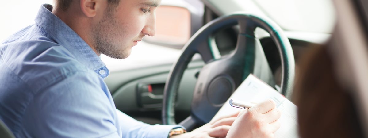 Ilustrační stock: řidič v automobilu drží v ruce ručně psanou výpověď pojistné smlouvy a kontroluje datum na kalendáři na palubní desce, venkovní světlo, civilně, bez loga