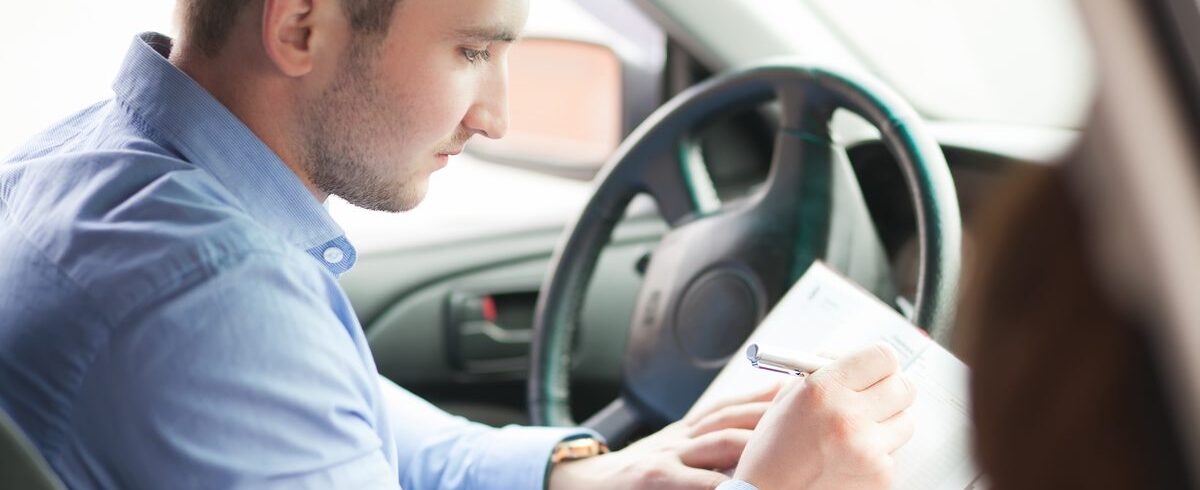 Ilustrační stock: řidič v automobilu drží v ruce ručně psanou výpověď pojistné smlouvy a kontroluje datum na kalendáři na palubní desce, venkovní světlo, civilně, bez loga